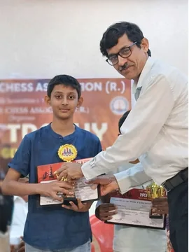 Amogha receiving a trophy from an official