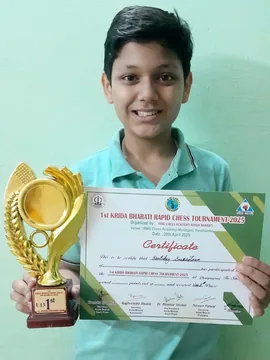Dhruv holding a large trophy and a certificate from the Krida Bharati Rapid Chess Tournament