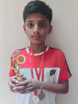 A student holding a trophy with two medals around their neck