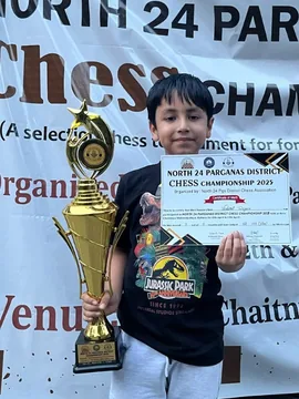 Vedant holding a trophy and certificate under the North 24 Parganas District Chess Championship banner